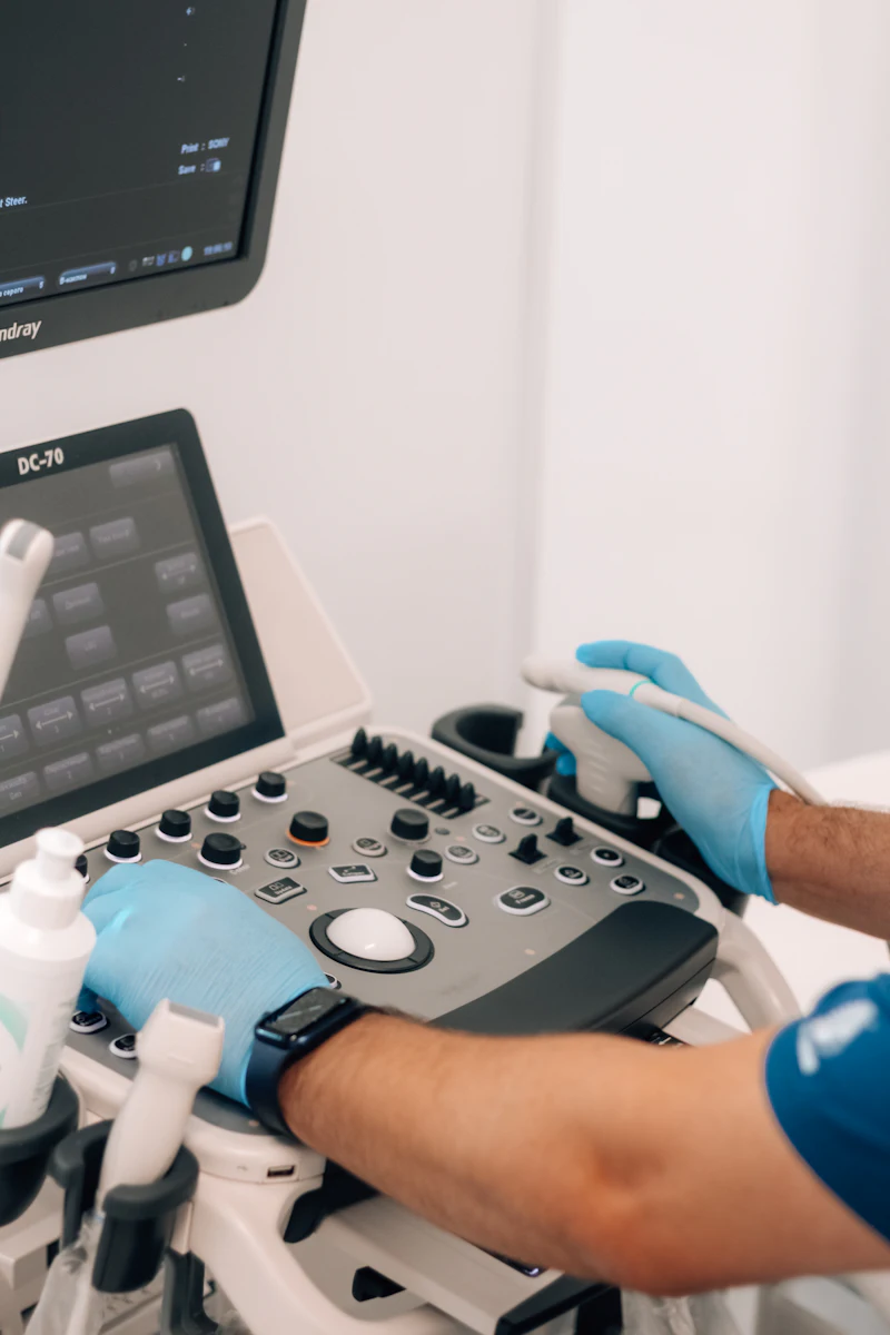 An engineer in blue gloves working an ultrasound console during testing